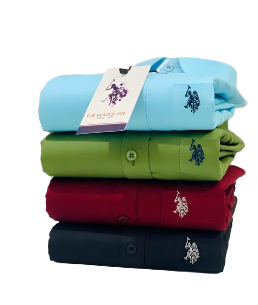 Stack of folded U.S. Polo Assn. shirts in blue, green, maroon, and navy with a visible brand tag.