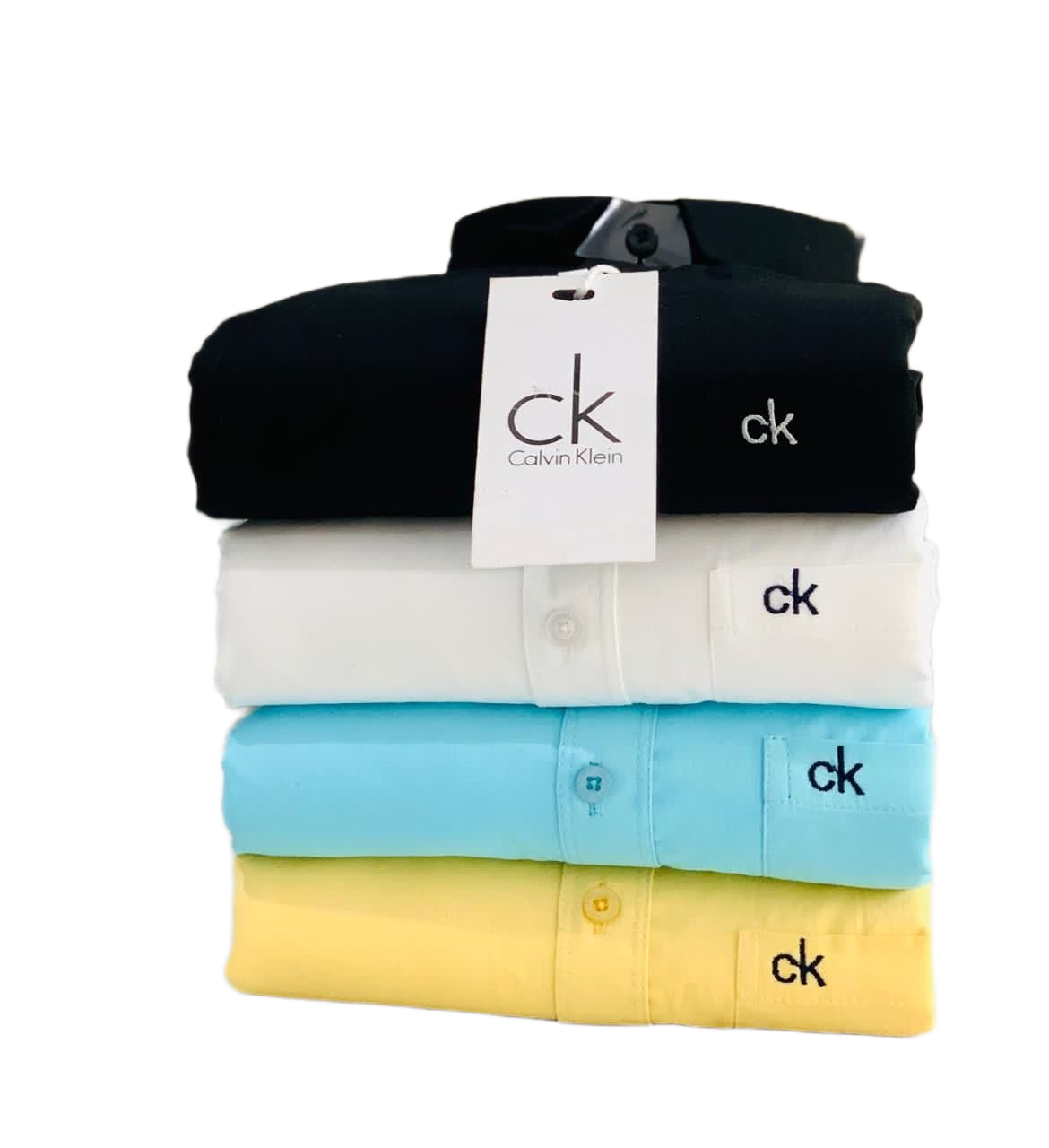 Stack of folded Calvin Klein shirts in black, white, blue, and yellow with a visible tag.