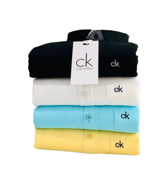 Stack of folded Calvin Klein shirts in black, white, blue, and yellow with a visible tag.